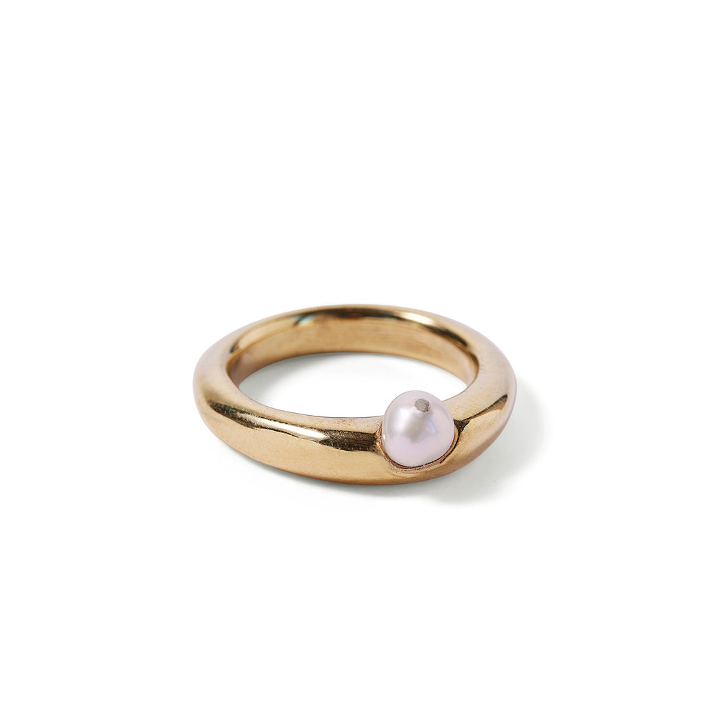 Goldplated ring with white pearl attached to hollowed out space reaching halfway into depth of ring.