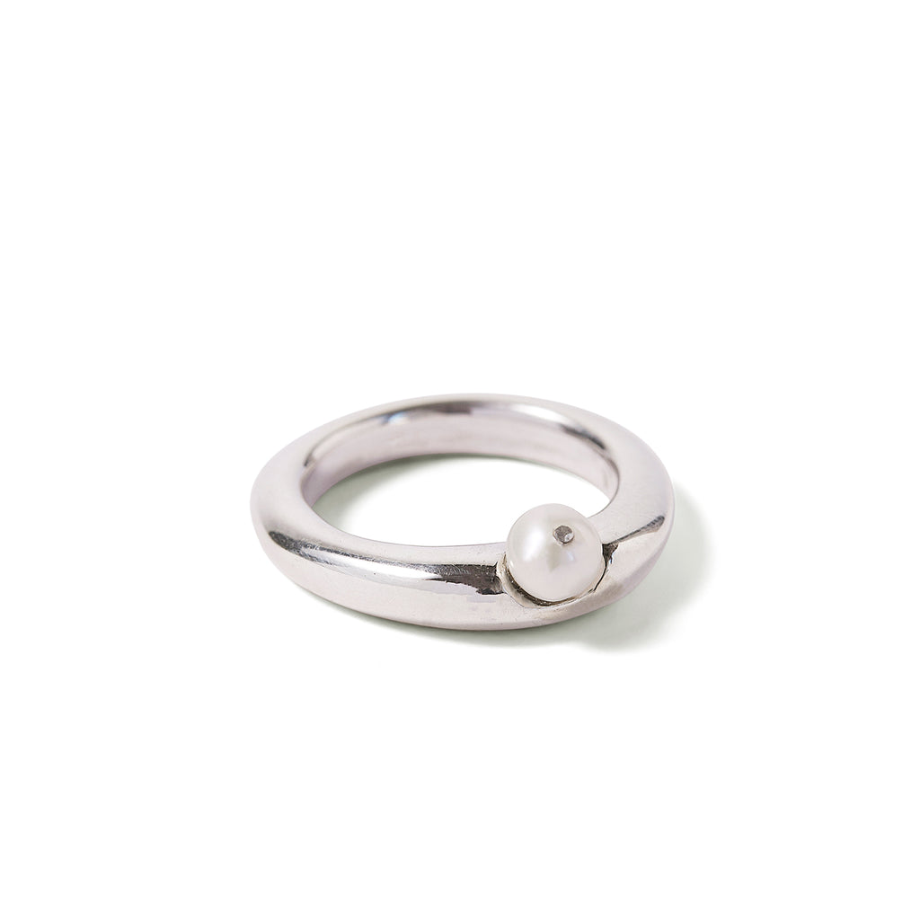 Silver ring with white pearl attached to hollowed out space reaching halfway into depth of ring.